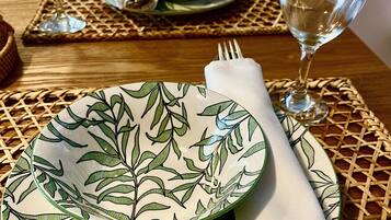 Una mesa de comedor dispuesta con dos platos, dos vasos y un servilleta doblada.