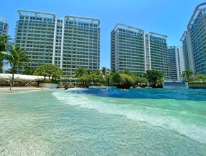 A hotel with multiple high-rise buildings, a swimming pool, and palm trees. - Azure Urban Resort by Adam's Crib (Parañaque)