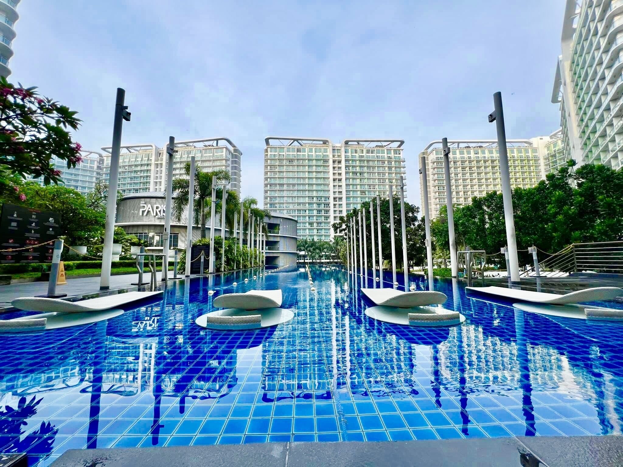 Una piscina al aire libre, sombrillas, sillones reclinables de piscina