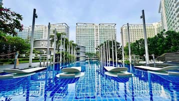 Una piscina al aire libre, sombrillas, sillones reclinables de piscina