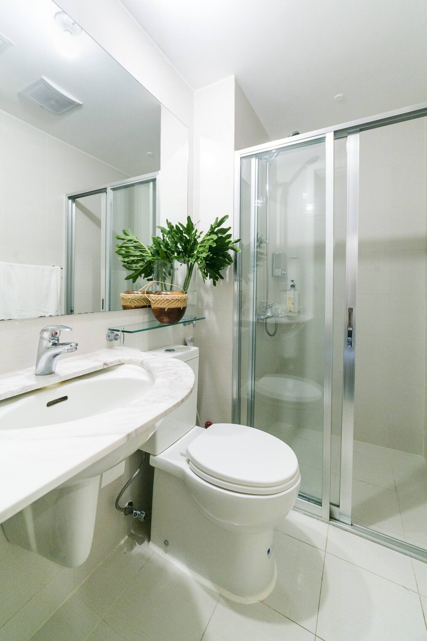 Um banheiro moderno com box de vidro, pia branca e vaso sanitário.