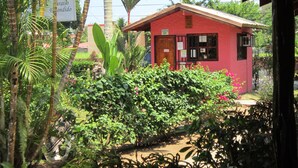 A small red building with a reception area, surrounded by lush greenery and palm trees. - Paraíso Escondido (Jacó)