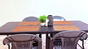 Uma mesa com duas cadeiras, um vaso de planta e um vaso decorativo.