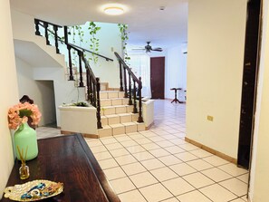A staircase with a wooden handrail, a ceiling fan, and a door in the background. - Casa Baraka, Cerca de Malecón, Centro Histórico y Playas (Mazatlán)