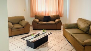 Sala de estar com dois sofás, uma mesa de centro e uma janela com cortinas.