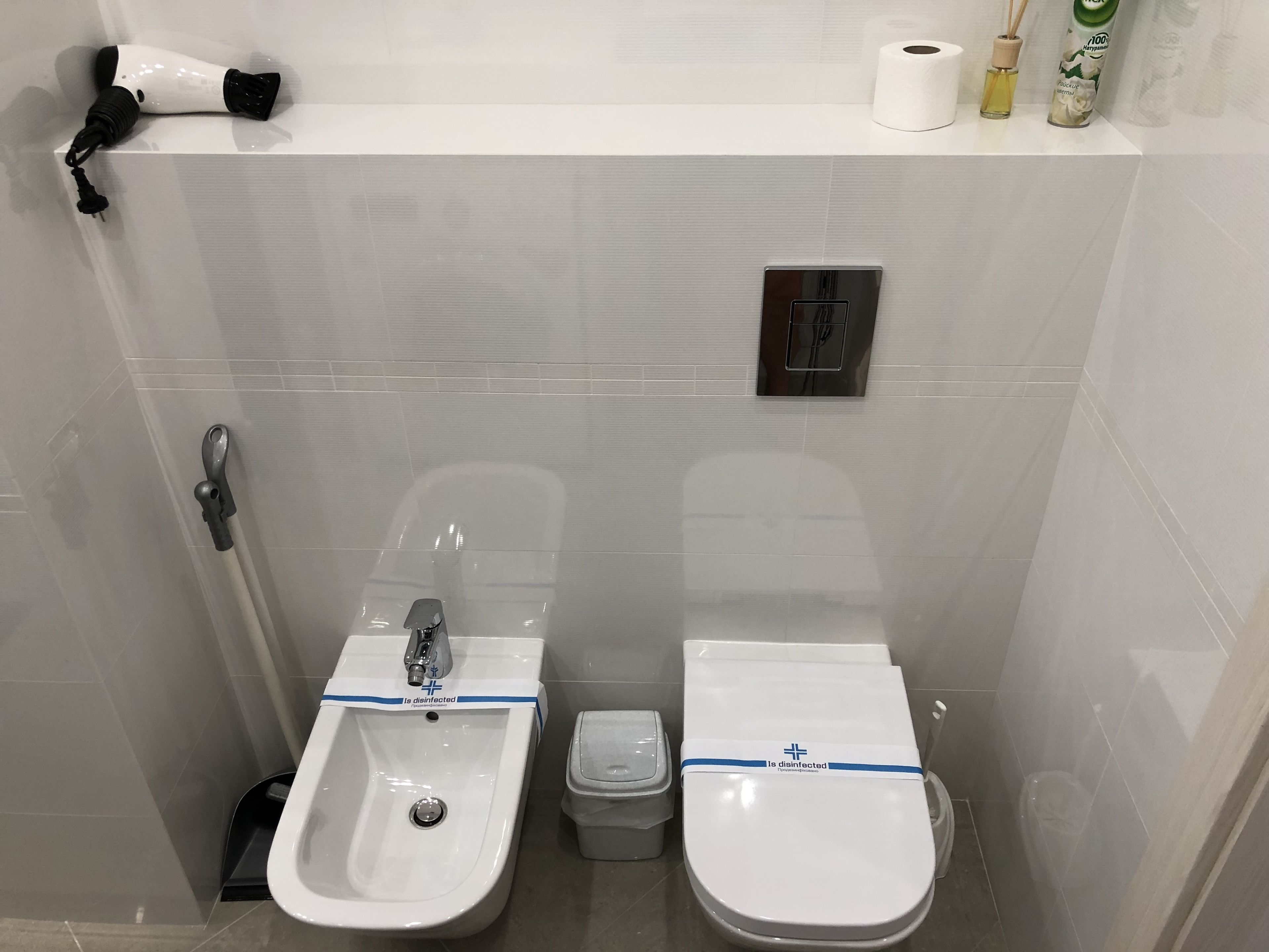 A bathroom with two sinks, a toilet, and a trash bin.