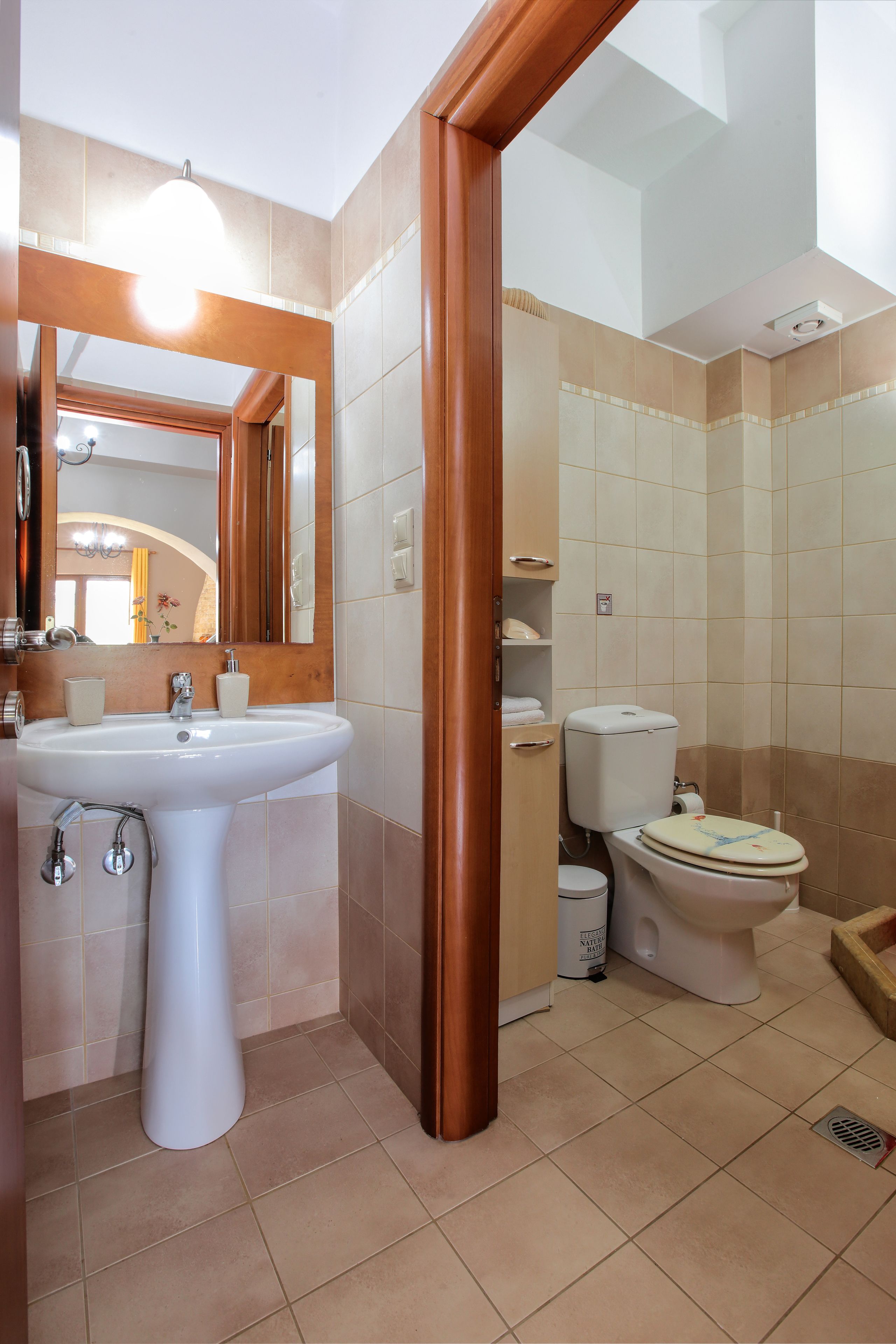 A bathroom with a sink, toilet, and mirror.