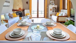 A modern hotel room with a dining area, a fireplace, and a balcony with yellow curtains. - Valena Stylish Home -15 min to Elafonisi (Kissamos)
