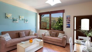 A living room with two sofas, a coffee table, and a dining table set with plates and a vase. - Valena Stylish Home -15 min to Elafonisi (Kissamos)