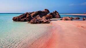 A beach with clear turquoise water, a sandy shore, and large rocks. - Valena Stylish Home -15 min to Elafonisi (Kissamos)