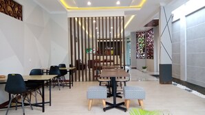 Un área de comedor moderna con una mesa de madera, sillas negras y un separador decorativo.