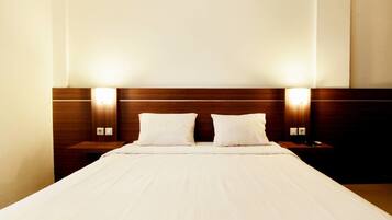 Een hotelkamer met een groot bed, twee nachtkastjes en wandlampen.