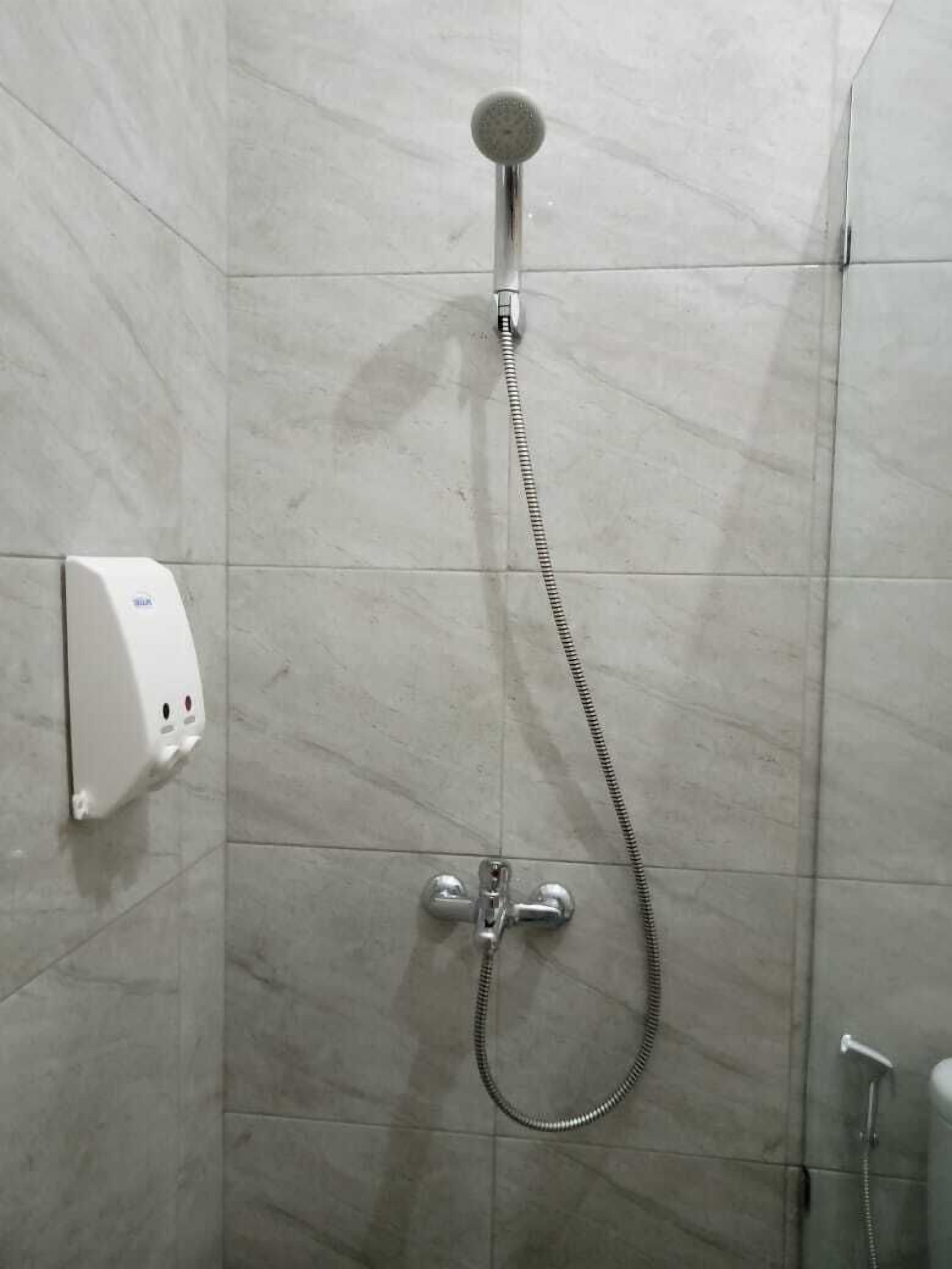 Una ducha con cabezal de ducha de mano y panel de control en la pared.