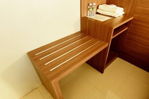 Um banco de madeira com assentos em ripas e uma mesa de madeira com uma toalha e artigos de higiene.