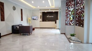 Una zona de recepción moderna con un mostrador, un sofá y un panel decorativo en la pared.