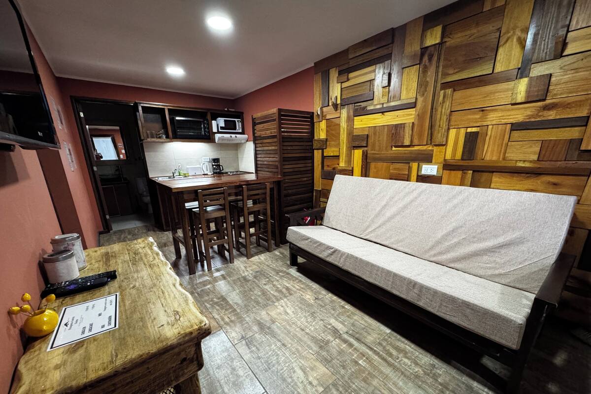 Ein gemütlicher Wohnbereich mit Sofa, Holztisch und Küchenzeile.