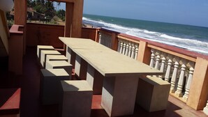 Un balcon avec vue sur l’océan, comprenant une longue table et des chaises.