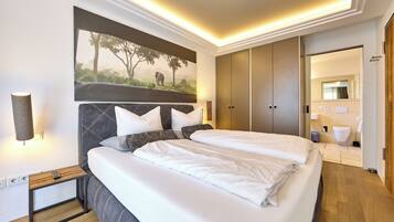 Ein modernes Hotelzimmer mit einem großen Bett, einem Kopfteil mit einer Naturmotiv-Abbildung, einem Nachttisch mit einer Lampe und einem Kleiderschrank.
