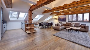 Un loft spacieux avec de hauts plafonds, des poutres apparentes, des fenêtres de toit, un coin repas et un espace salon confortable.