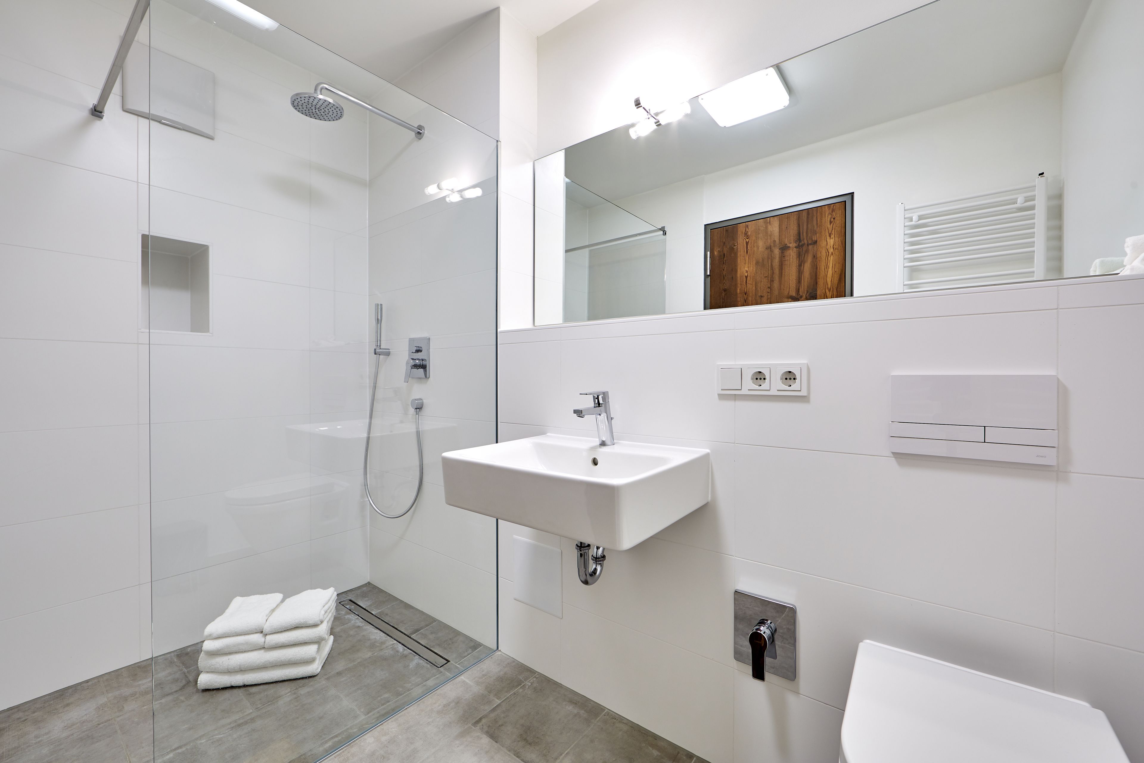 A modern bathroom with a glass-enclosed shower, a white sink, and a toilet.