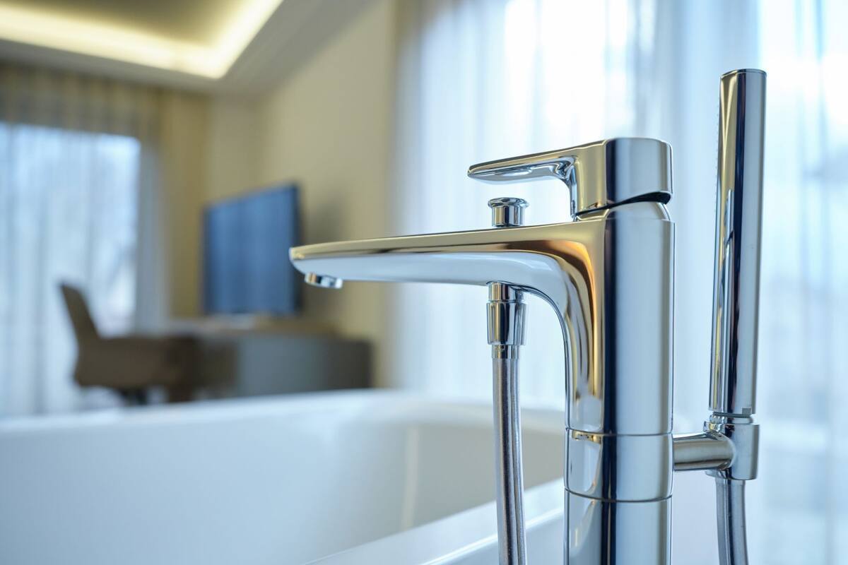 Un baño moderno con grifo cromado, bañera y televisión al fondo.