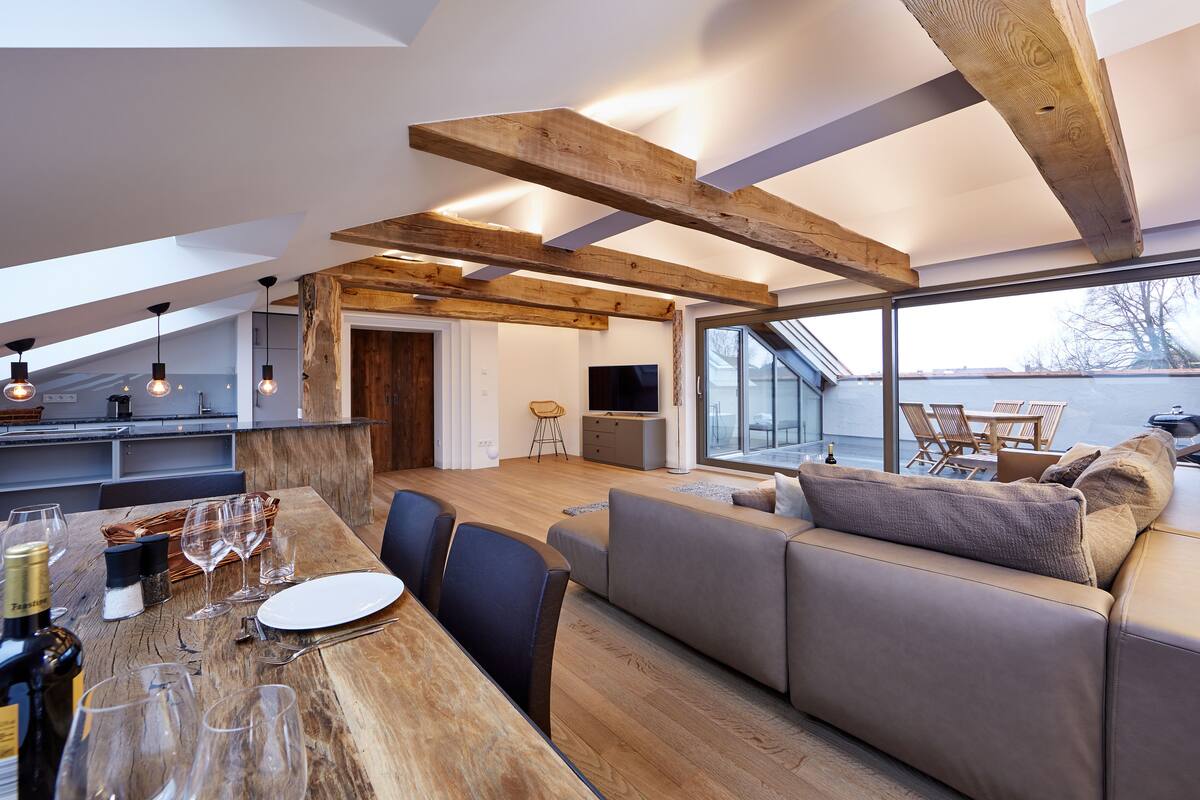 Un interior moderno con una mesa de comedor de madera, un sofá y un televisor en la sala.