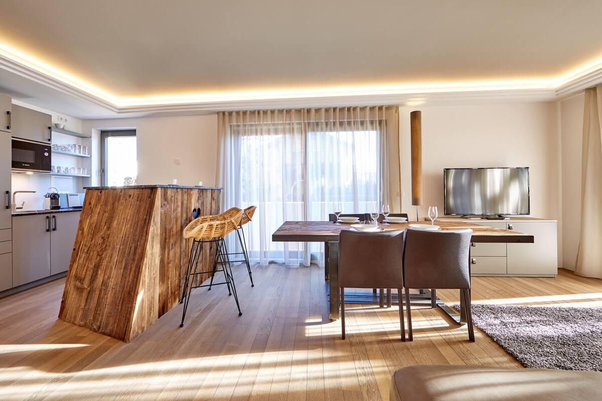 Una sala de estar moderna con comedor, cocina y televisor.