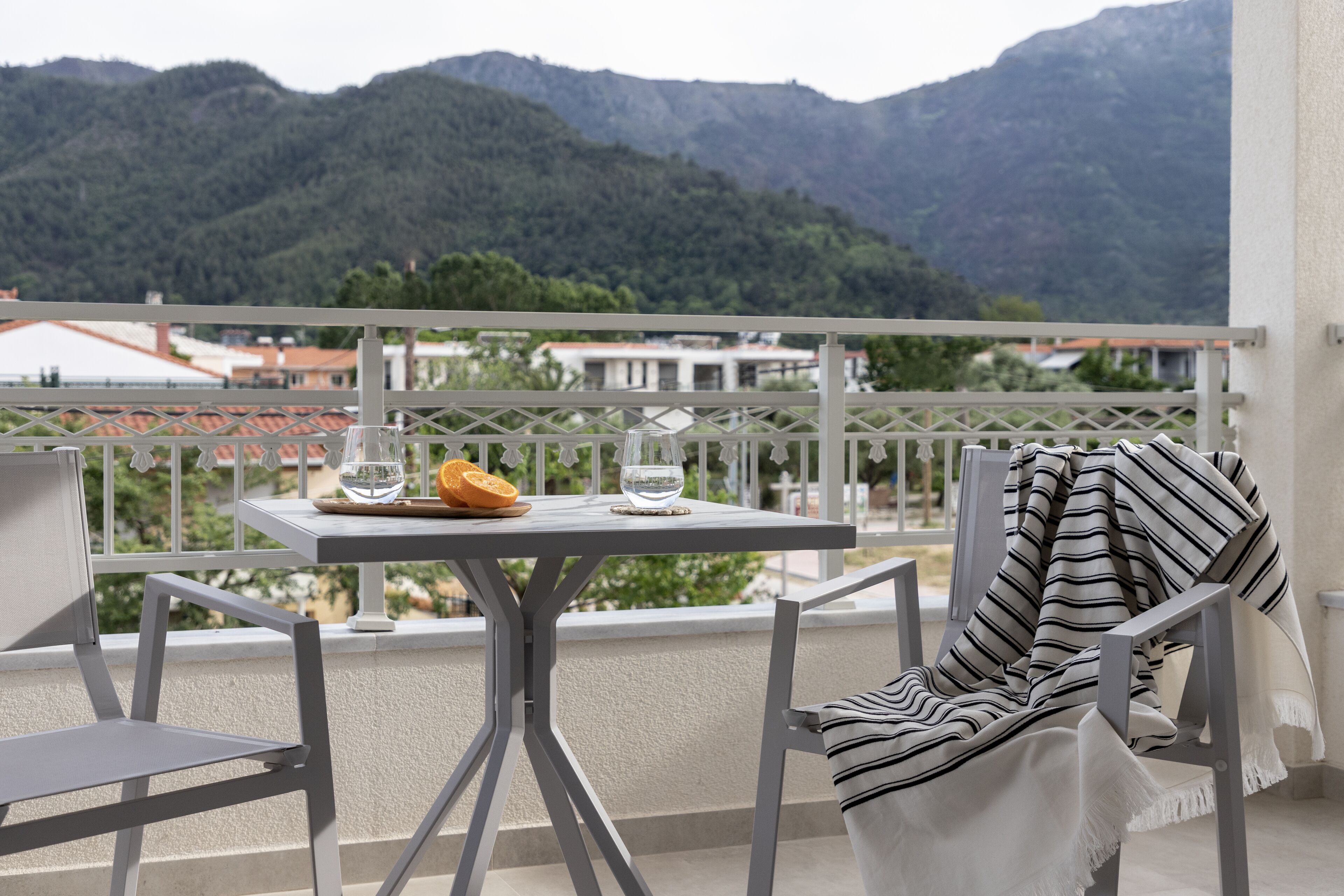 Un balcón con mesa, sillas y vistas a montañas.