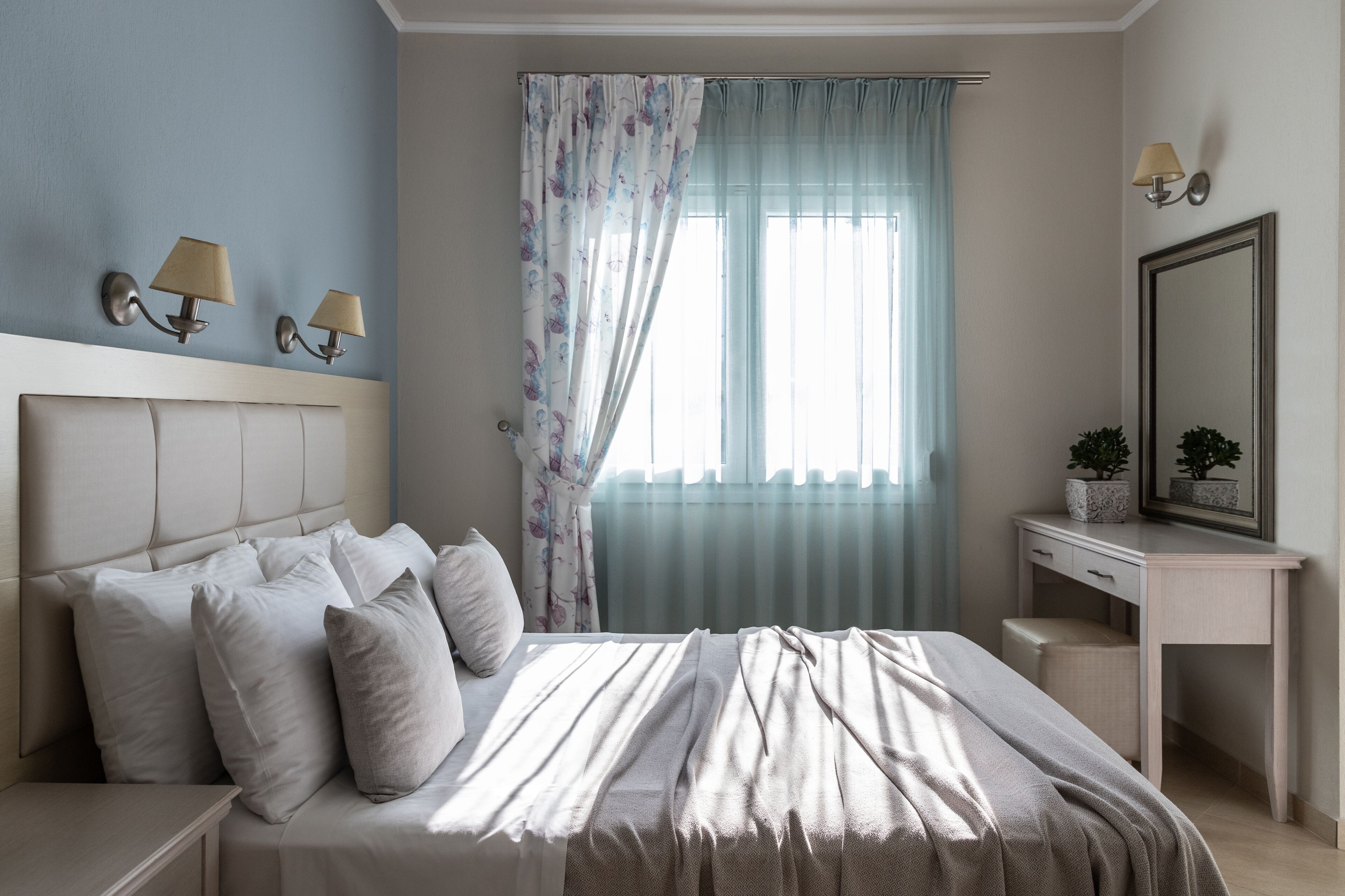 A bedroom with a bed, bedside tables, a dresser, and a mirror.