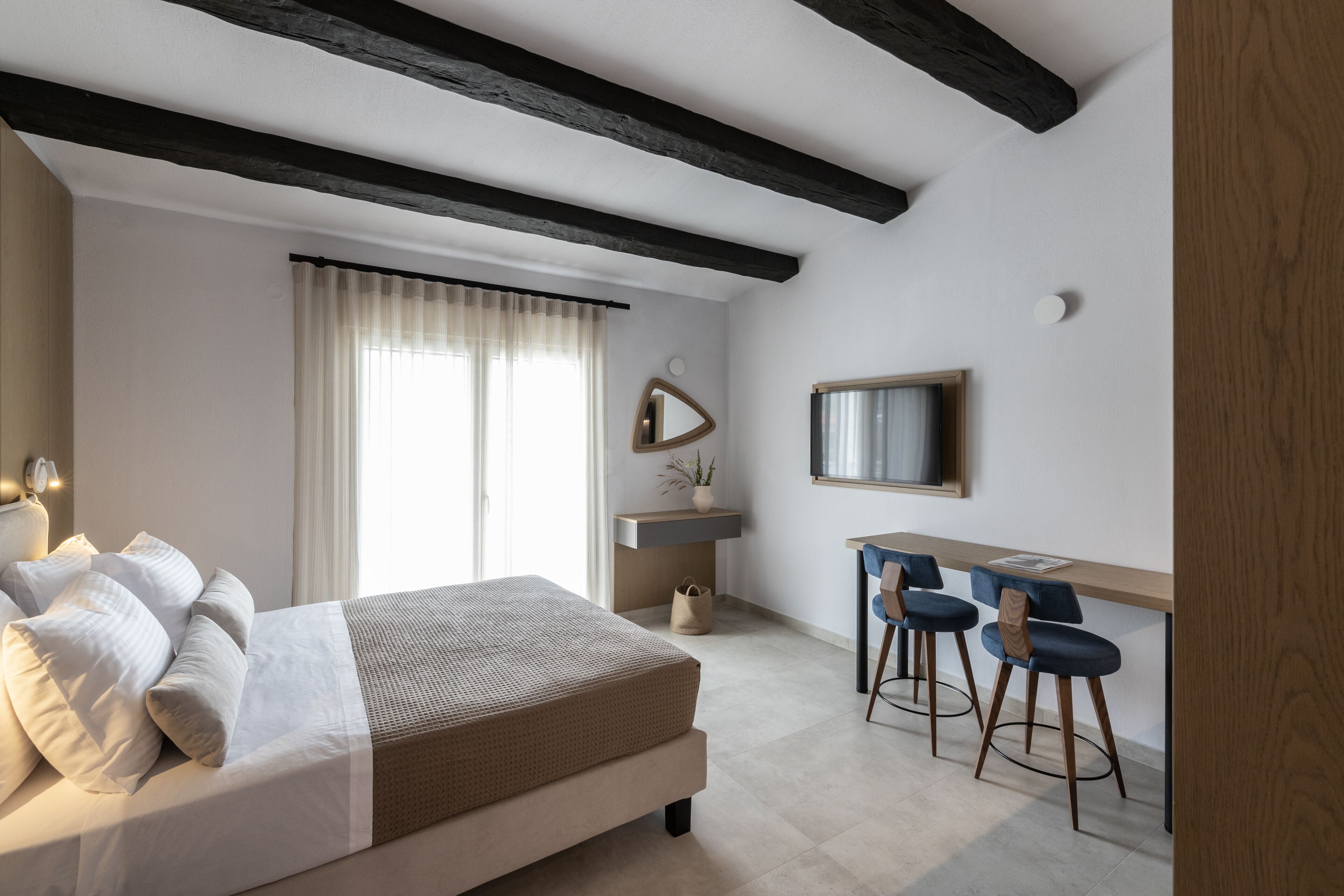 A bedroom with a bed, a desk, and two chairs.