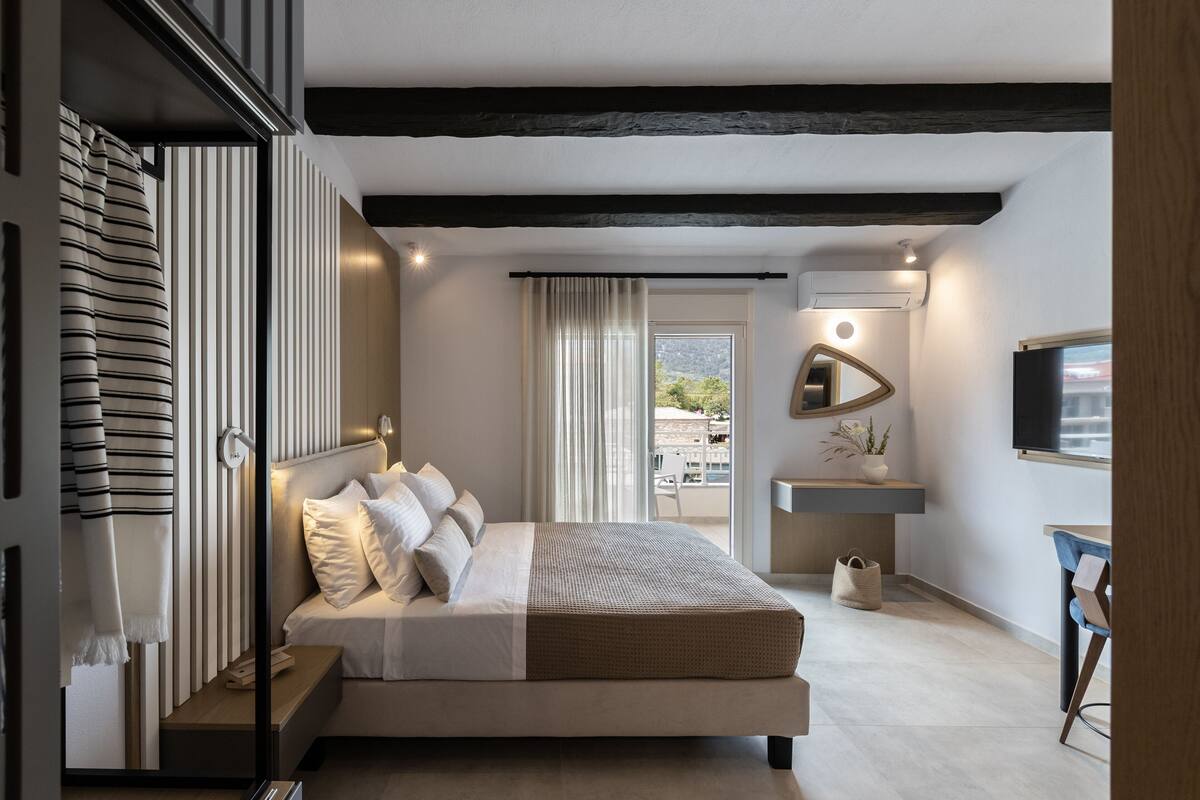 A modern bedroom with a bed, bedside table, and a view of the outdoors.