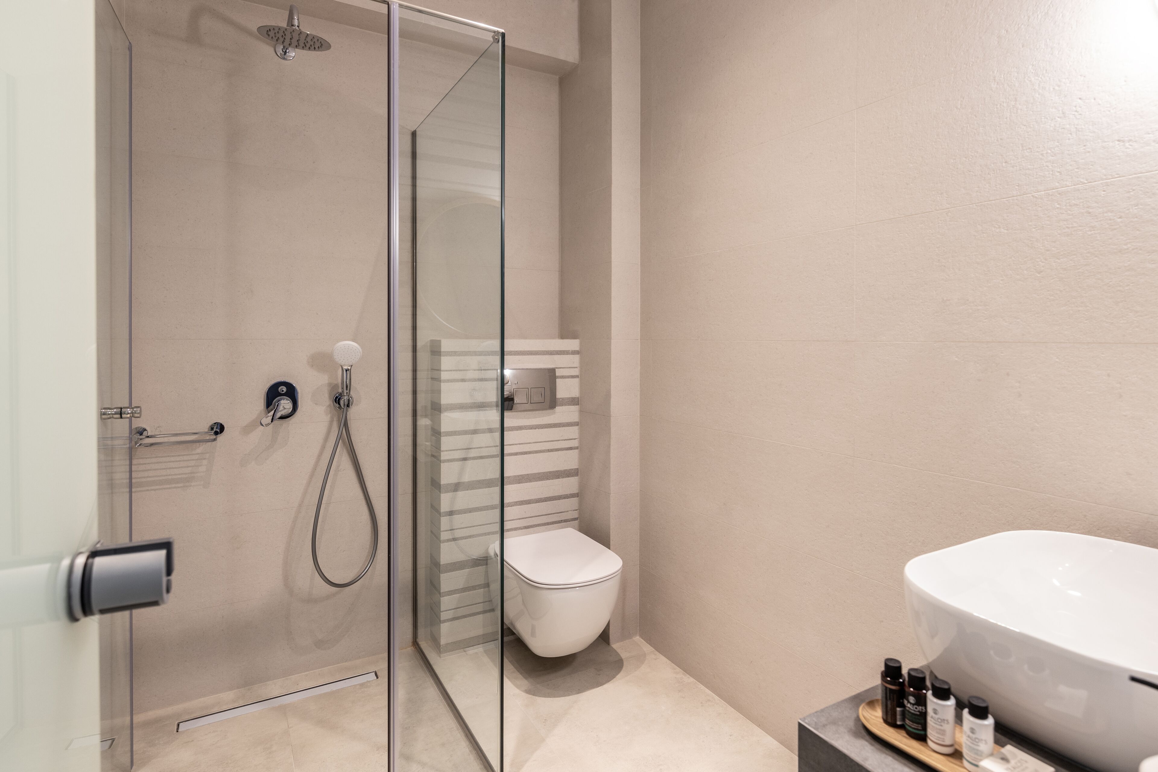 A modern bathroom with a glass-enclosed shower, a white toilet, and a large sink with toiletries.