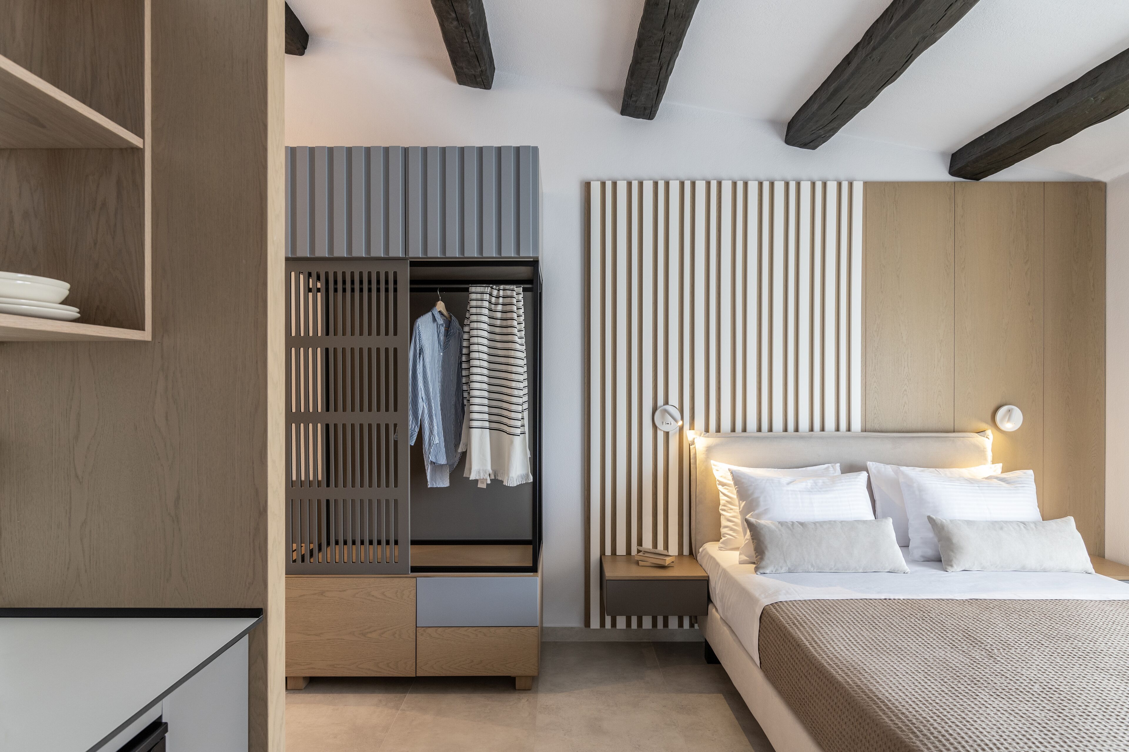 A modern bedroom with a bed, bedside tables, a wardrobe, and a built-in shelf.