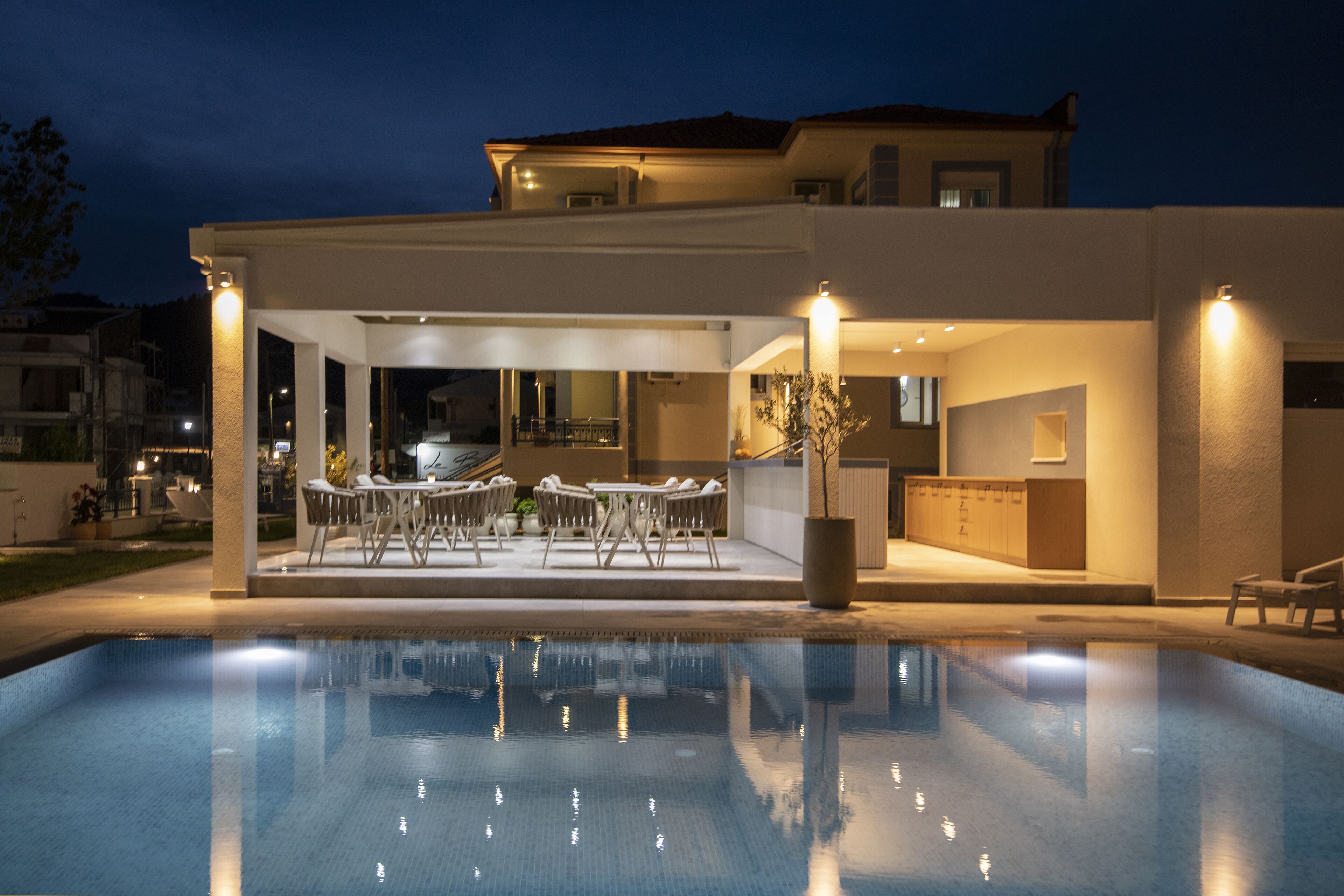 A modern house with a swimming pool, outdoor seating, and a well-lit patio area.