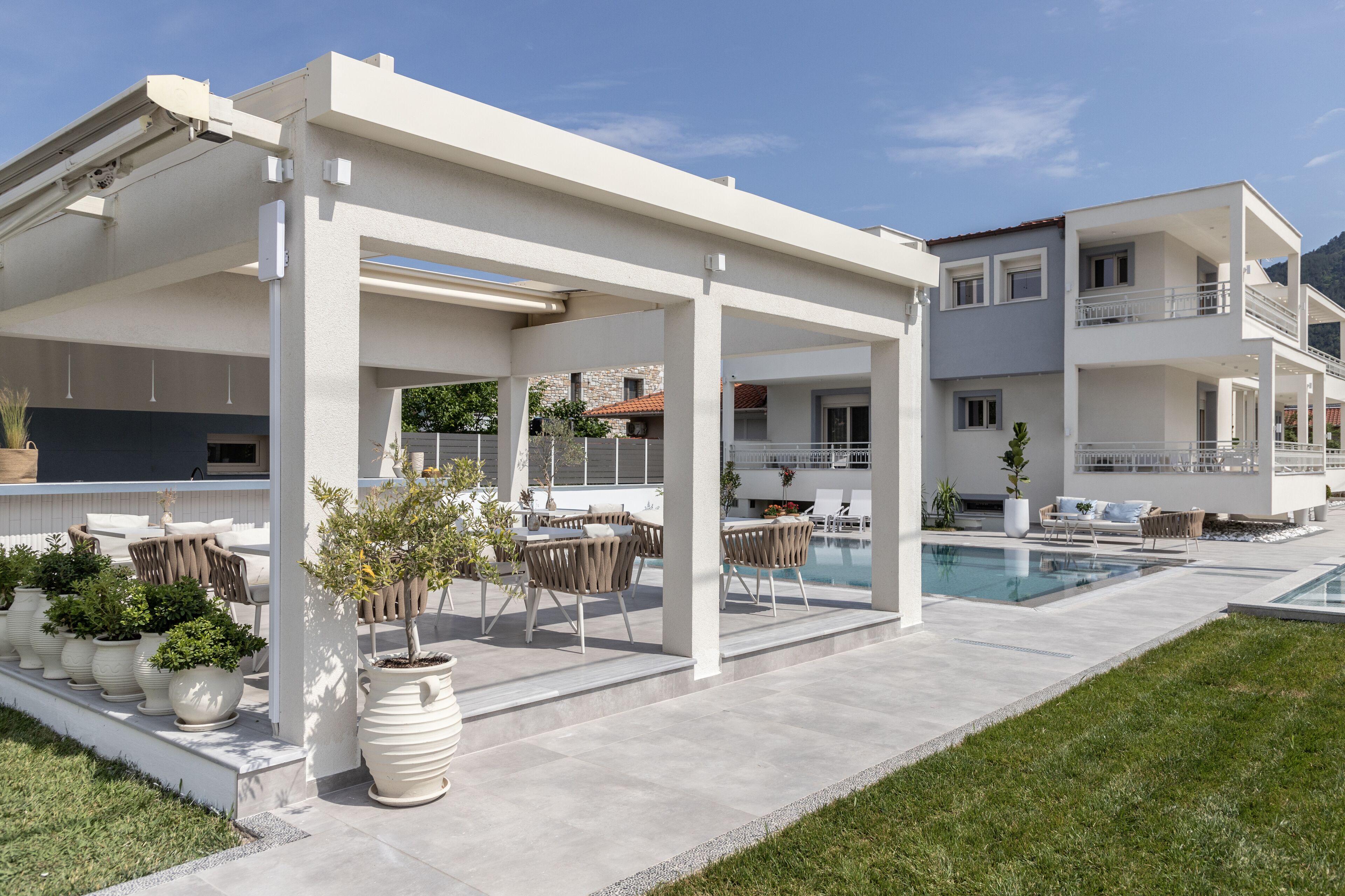 Et moderne poolområde med en overdækket patio, liggestole og plantekasser.