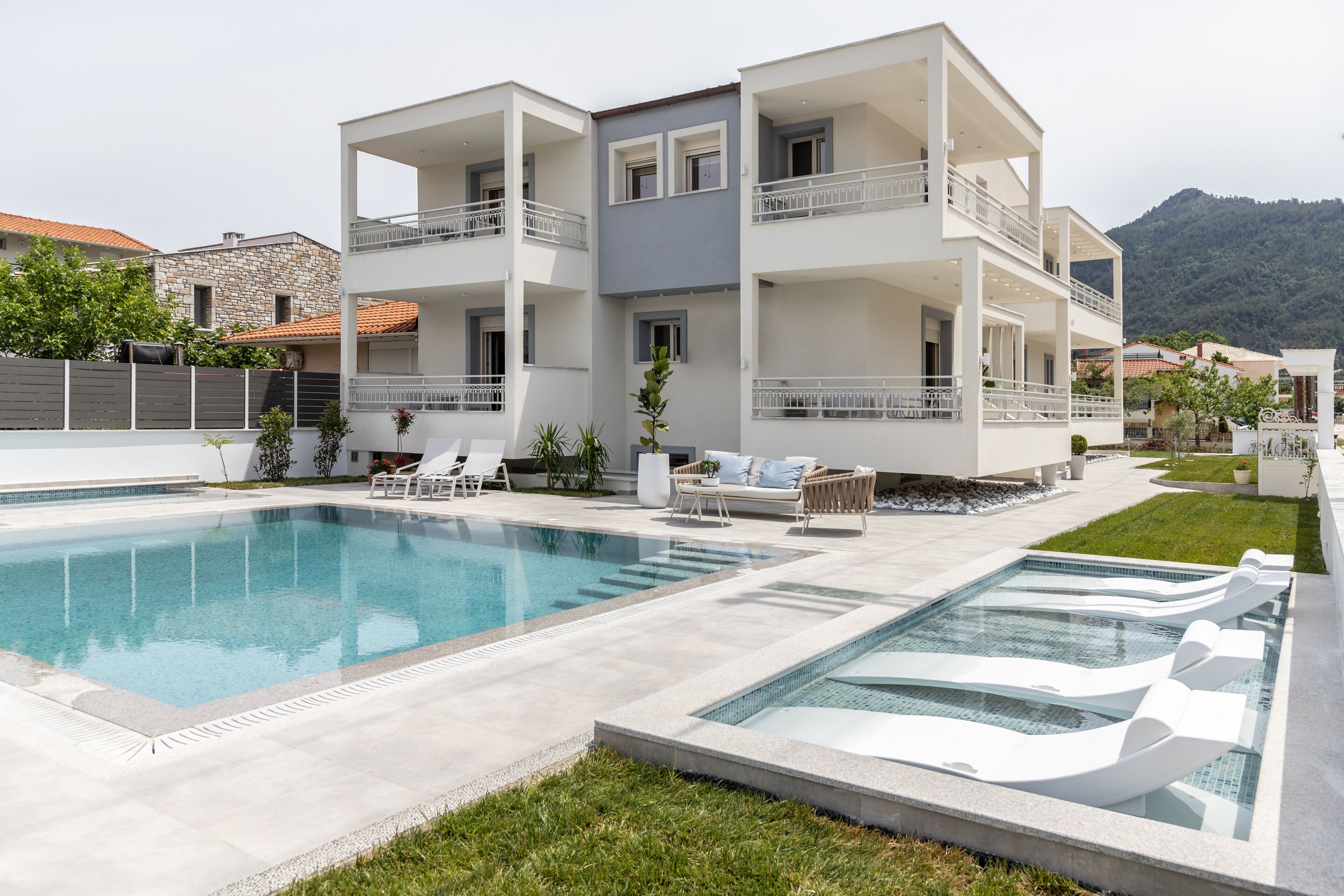 Un bâtiment moderne à deux étages, doté d’une piscine et d’un espace extérieur aménagé pour se détendre.