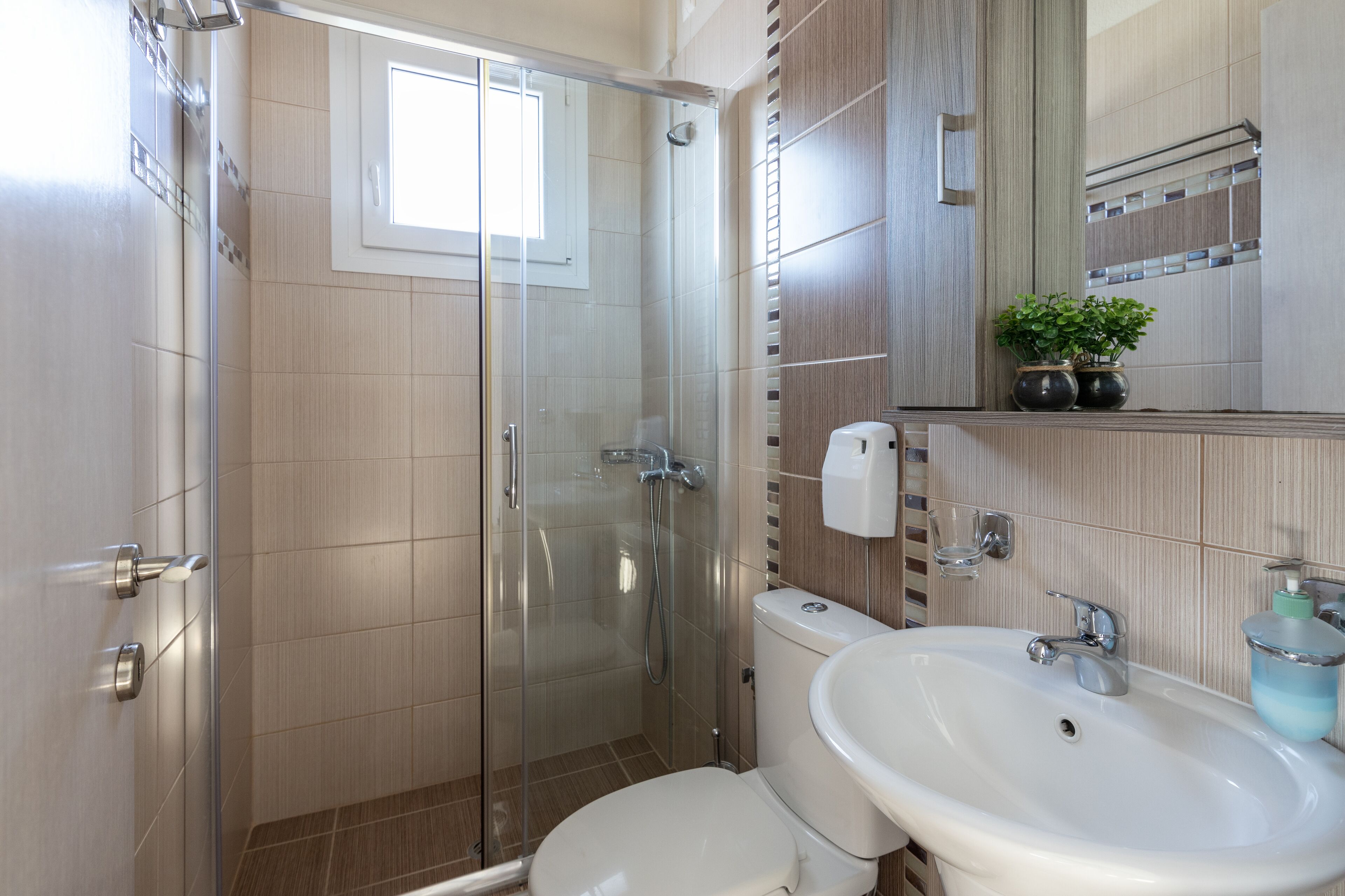 A modern bathroom with a glass shower enclosure, a white sink, and a toilet.