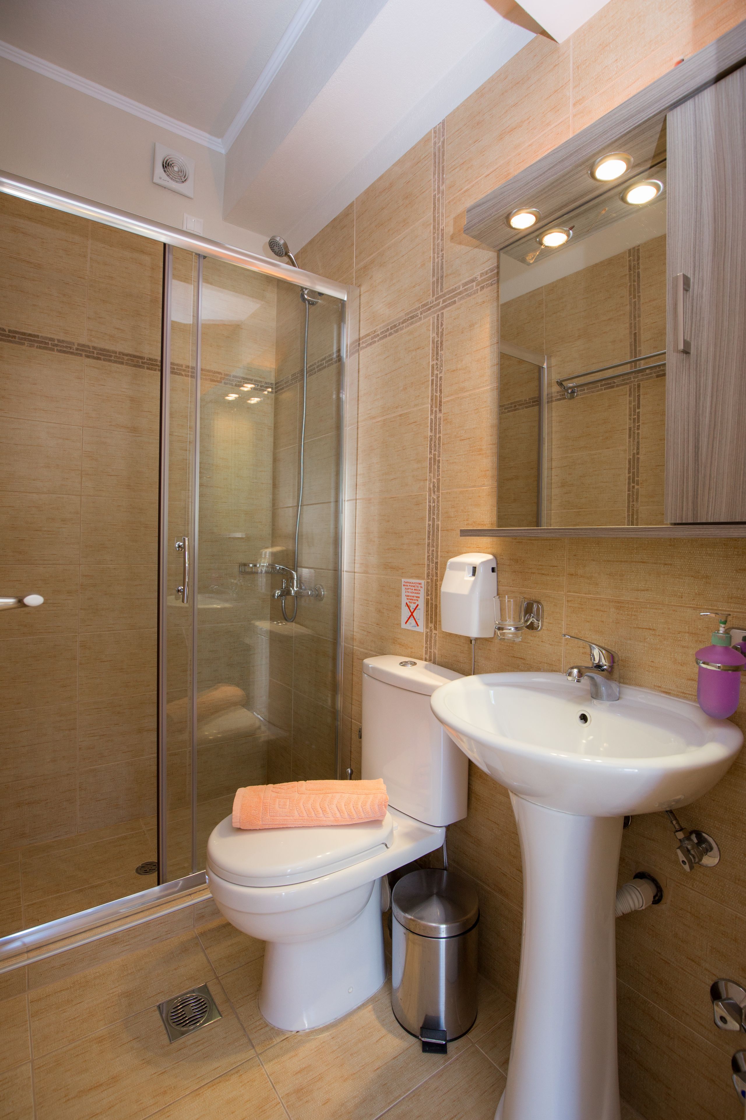 A bathroom with a glass-enclosed shower, a toilet, a sink, and a mirror.