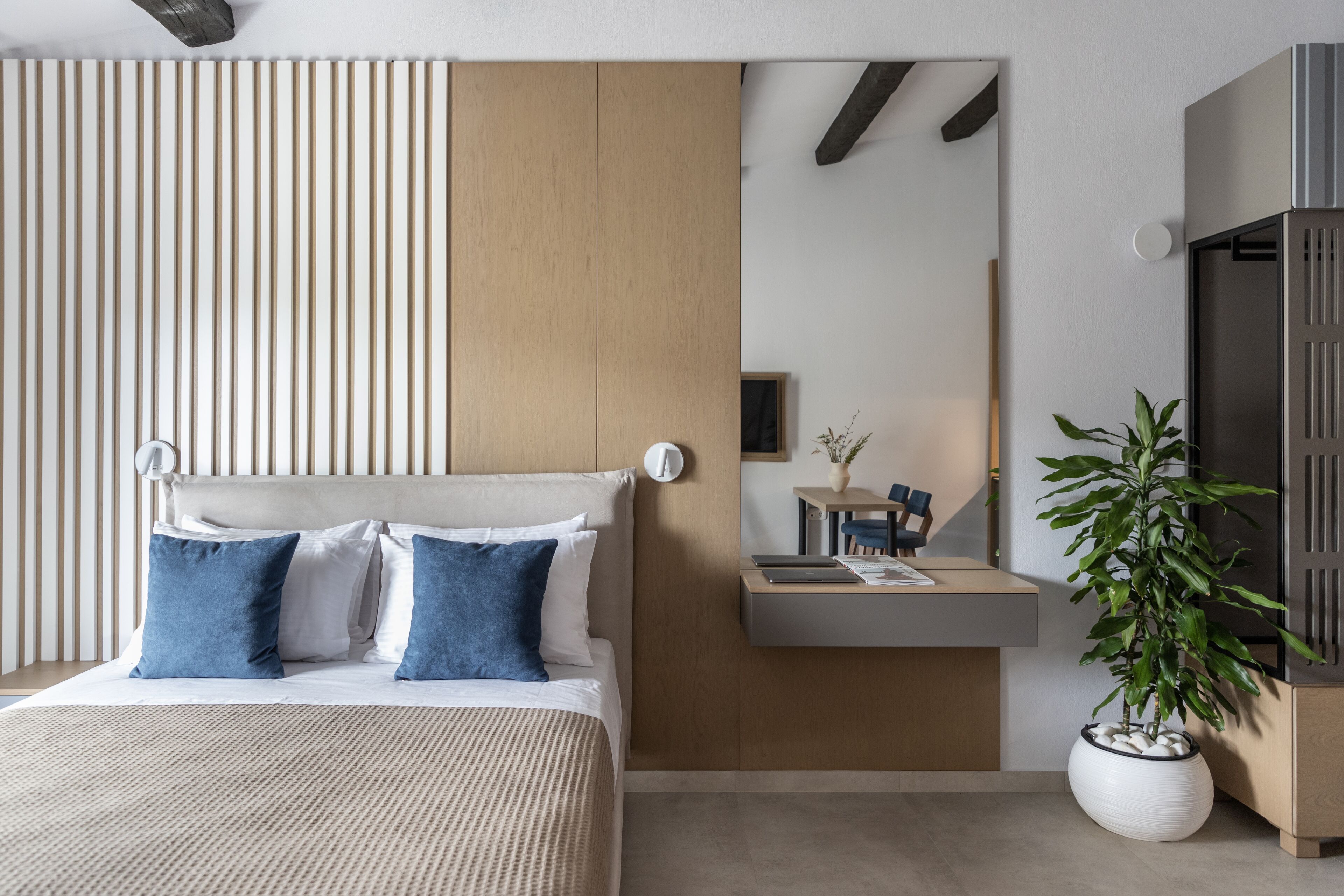 A modern bedroom with a bed, bedside table, and a potted plant.