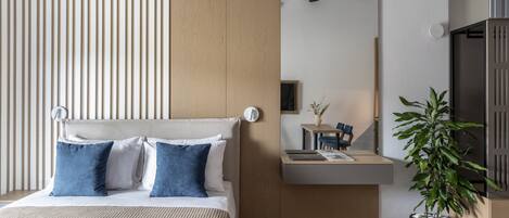 A modern bedroom with a bed, bedside table, and a potted plant.