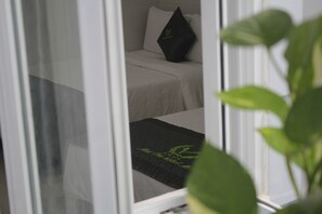 A hotel room with a bed, a pillow, and a window with a plant in the foreground. - Mai Tra Hotel (Quy Nhon Nam)
