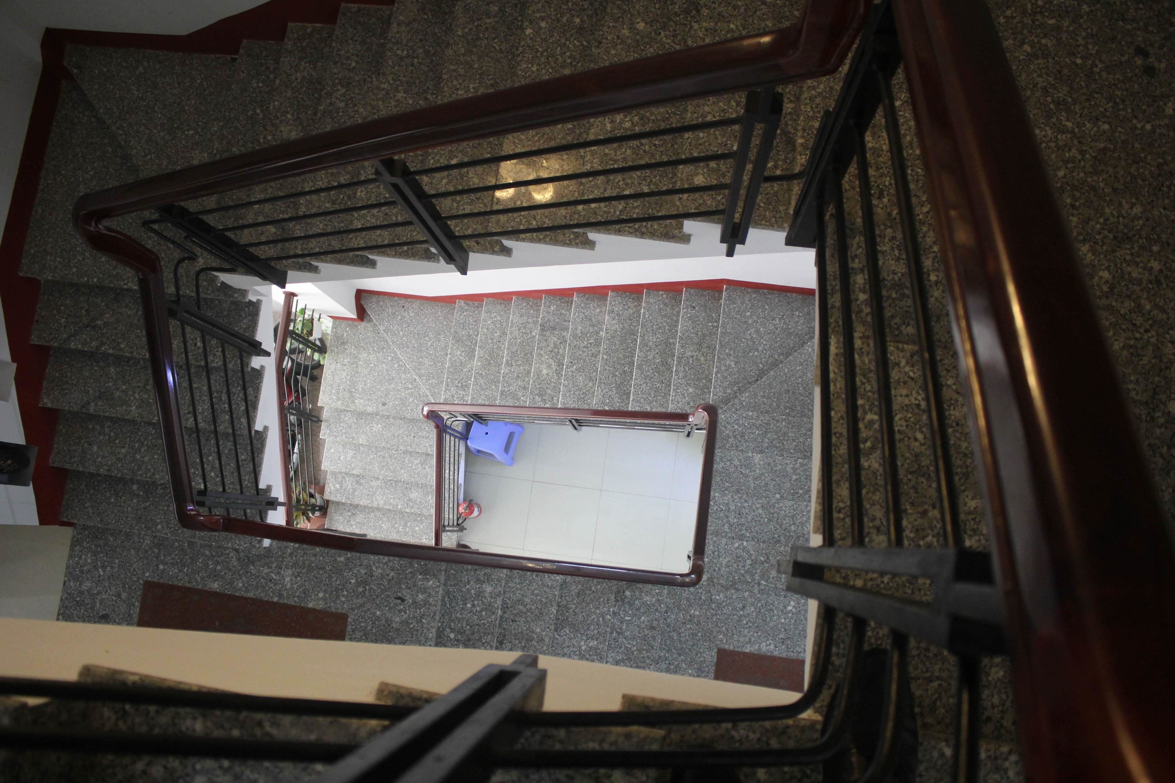 A staircase with a metal handrail and a white wall at the bottom.