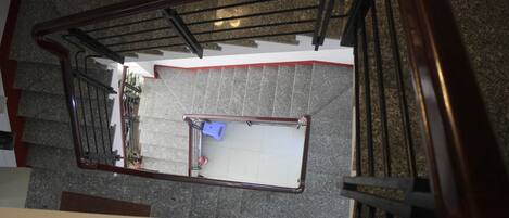 A staircase with a metal handrail and a white wall at the bottom.