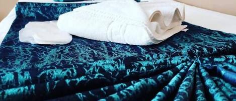 A bed with a tufted headboard, a dark blue patterned bedspread, and a white pillow.