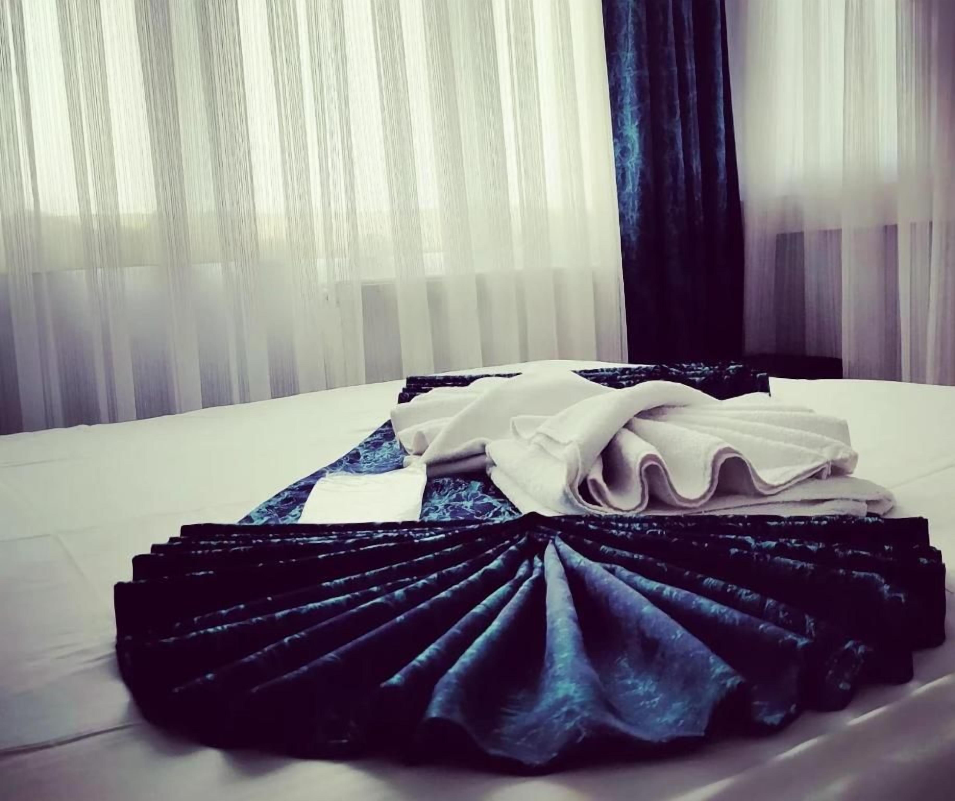A neatly made bed with folded linens and a decorative black and blue fabric arrangement.