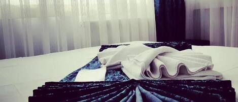 A neatly made bed with folded linens and a decorative black and blue fabric arrangement.
