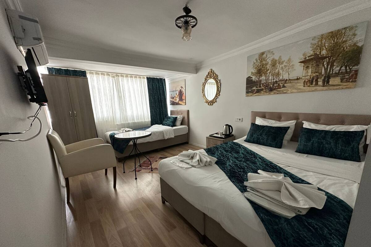 Habitación de hotel con cama, sofá, escritorio, silla, un cuadro y un espejo.