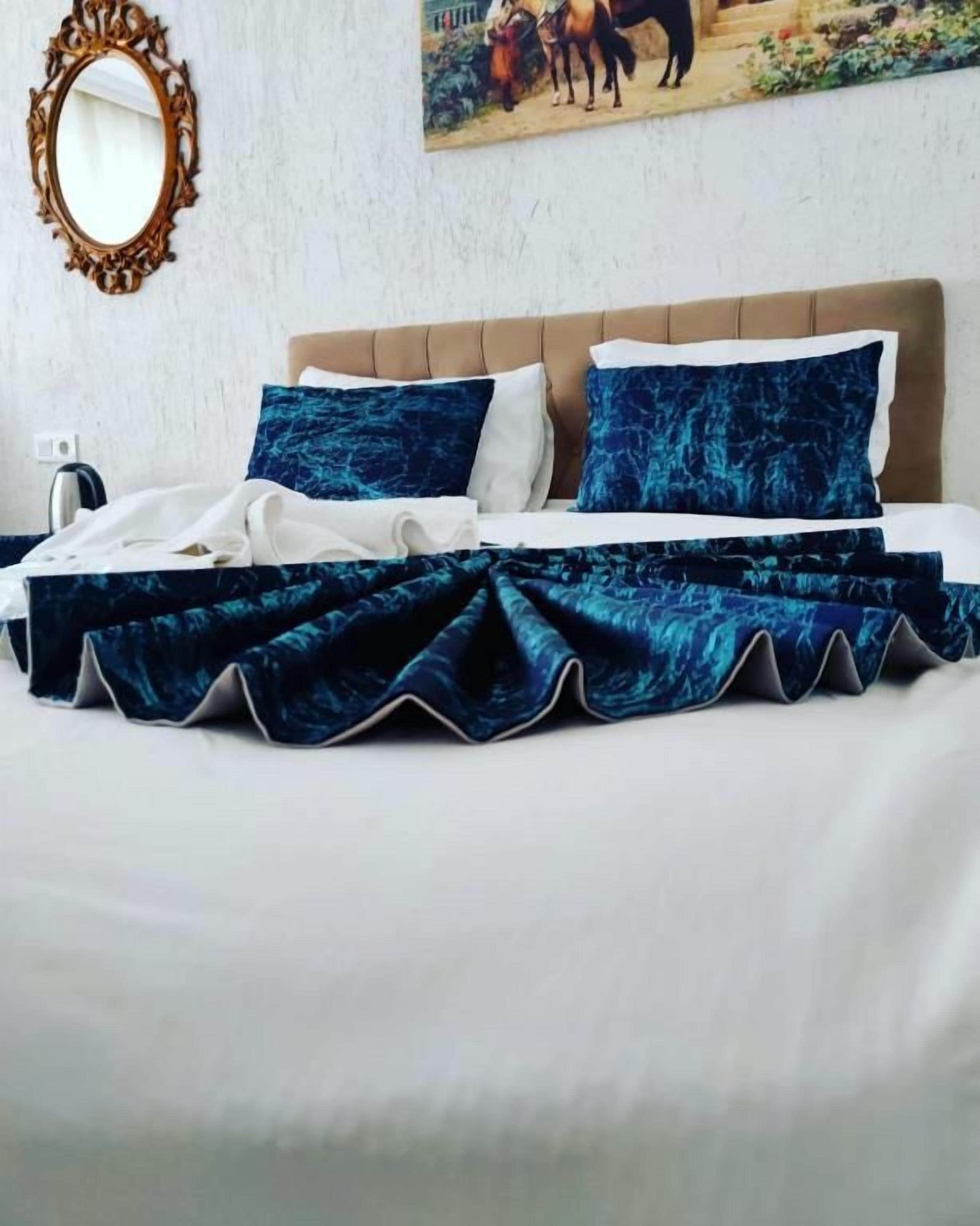 Un lit avec une tête de lit, des oreillers et une couvre-lit bleue.