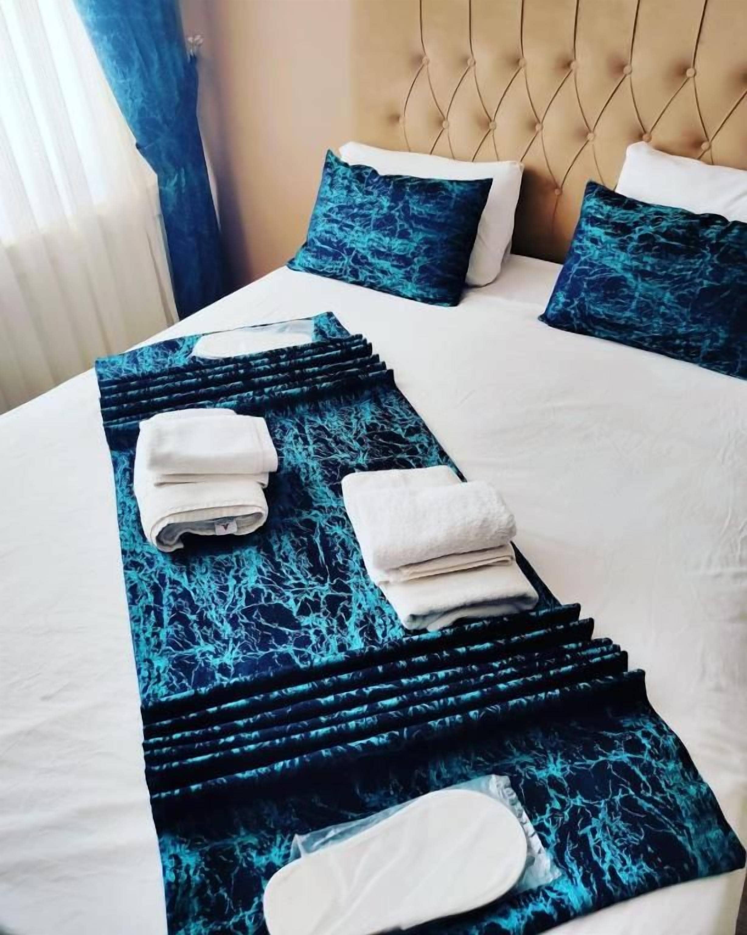 Un lit bien fait, avec une couvre-lit à motifs bleus, des oreillers blancs et une tête de lit.