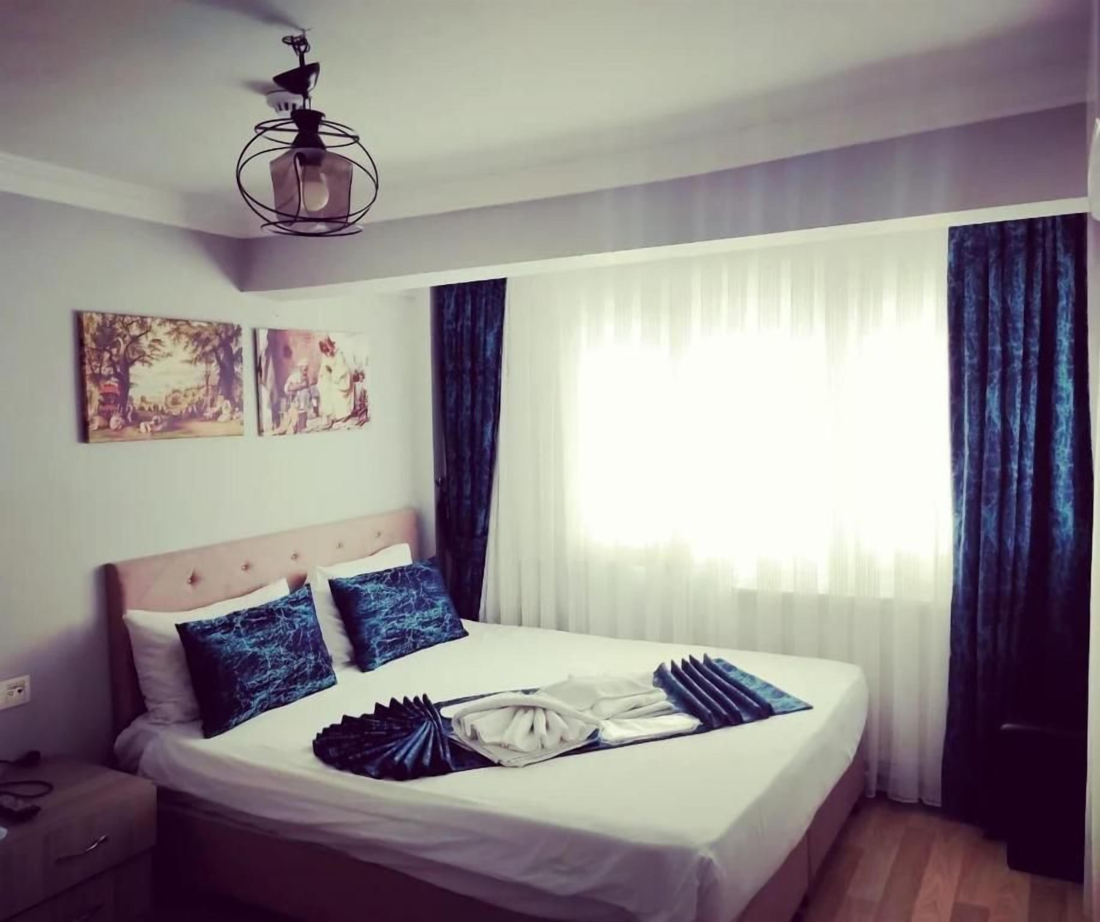 Ein Hotelzimmer mit Bett, Nachttisch, Lampe und Bildern an der Wand.
